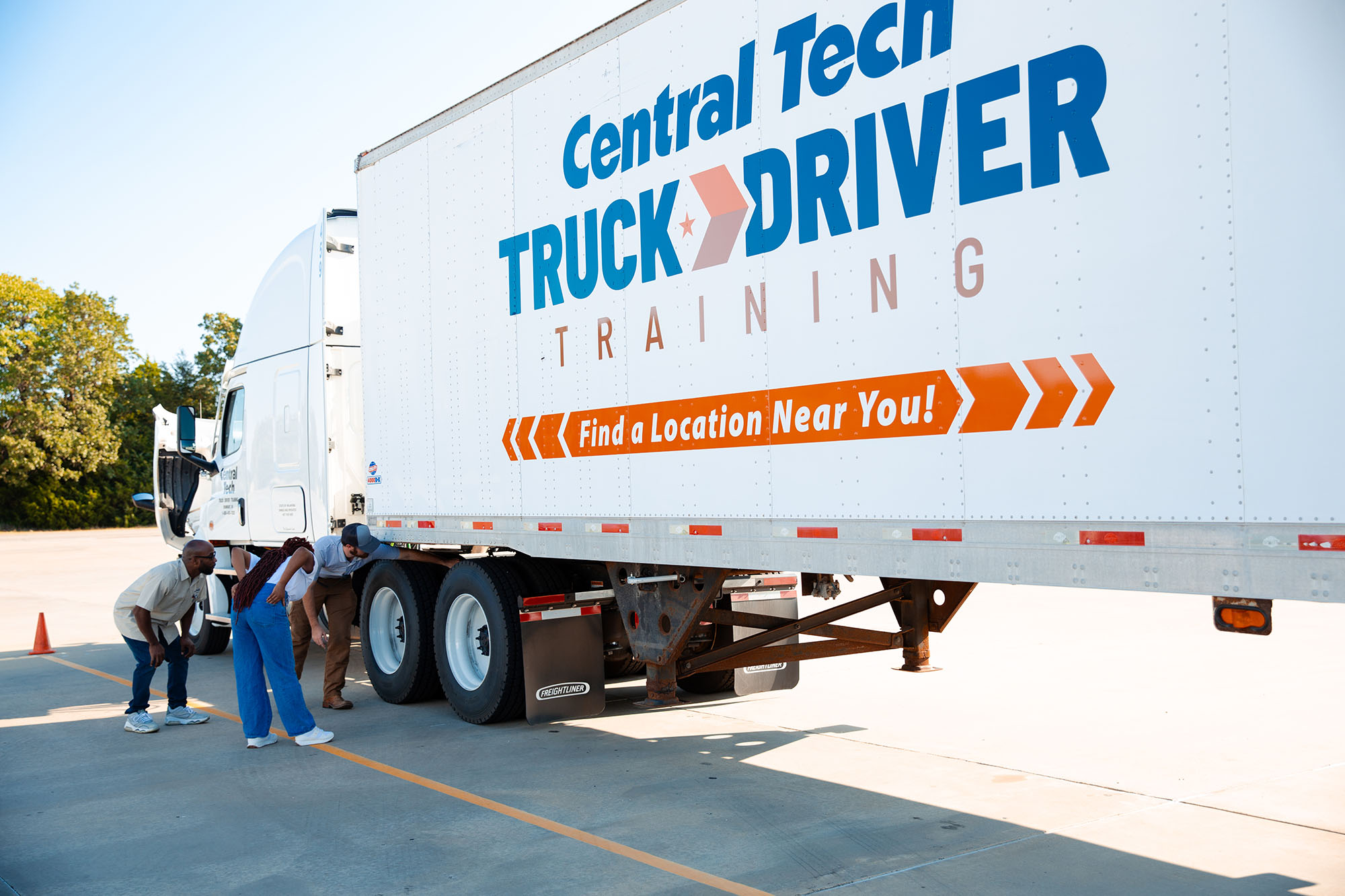 CDL instructor and students inspecting a semi truck