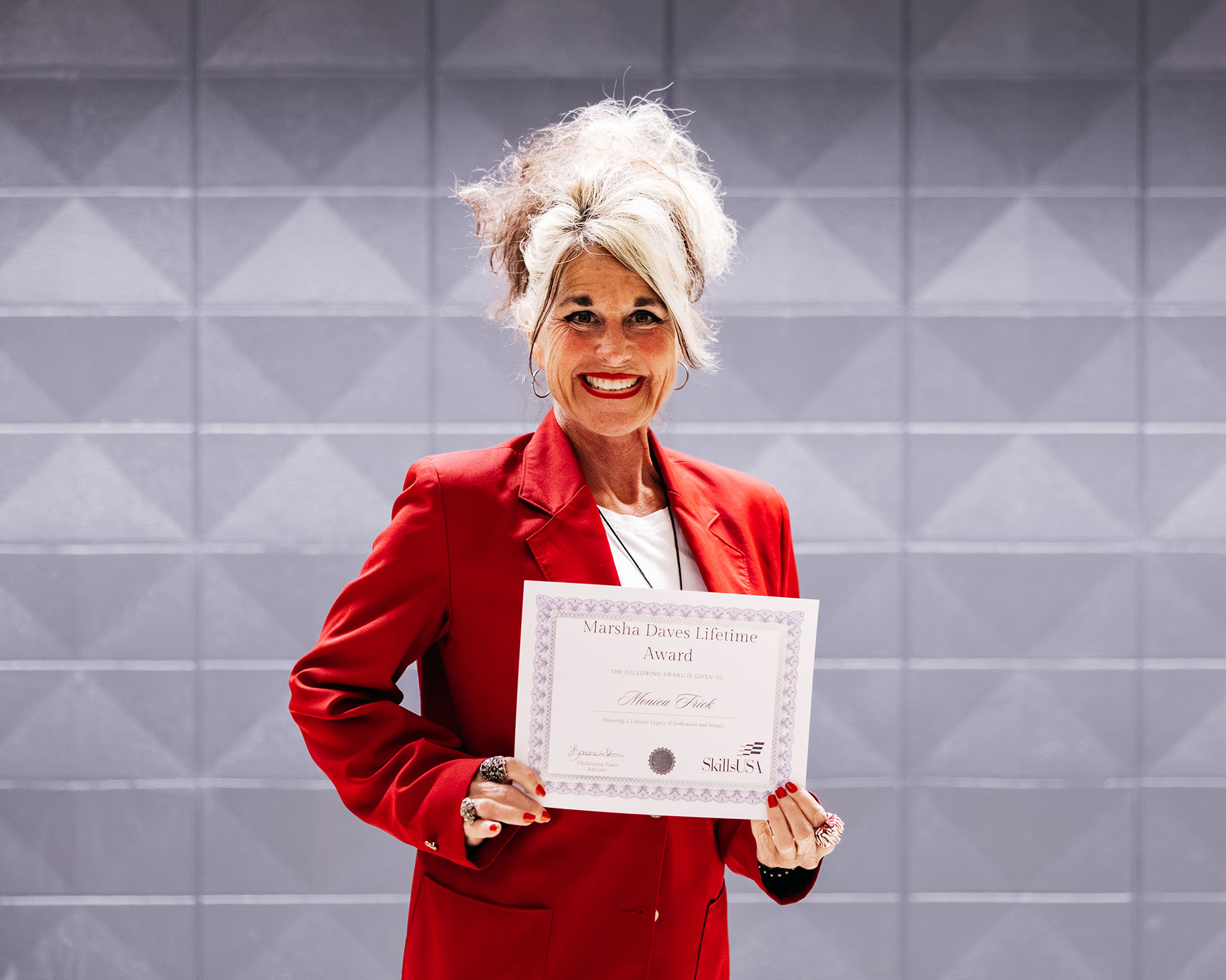 Monica Frick in her SkillsUSA jacket holding a certificate honoring her with the Marsha Daves Lifetime Achievement Award.
