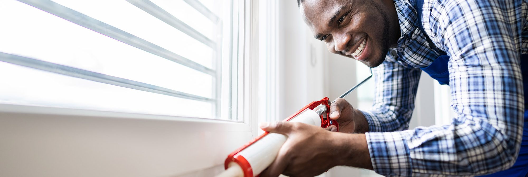 picture of a man caulking a window