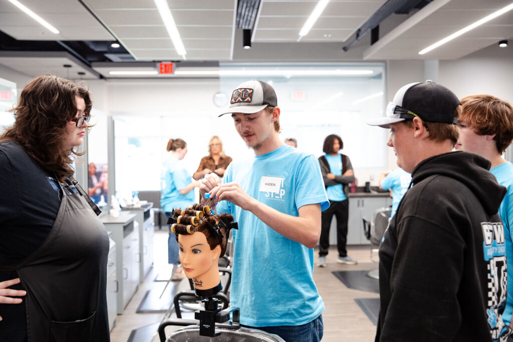students-take-turns-putting-rollers-mannequin-hair Students take turns putting rollers in a mannequin’s hair.